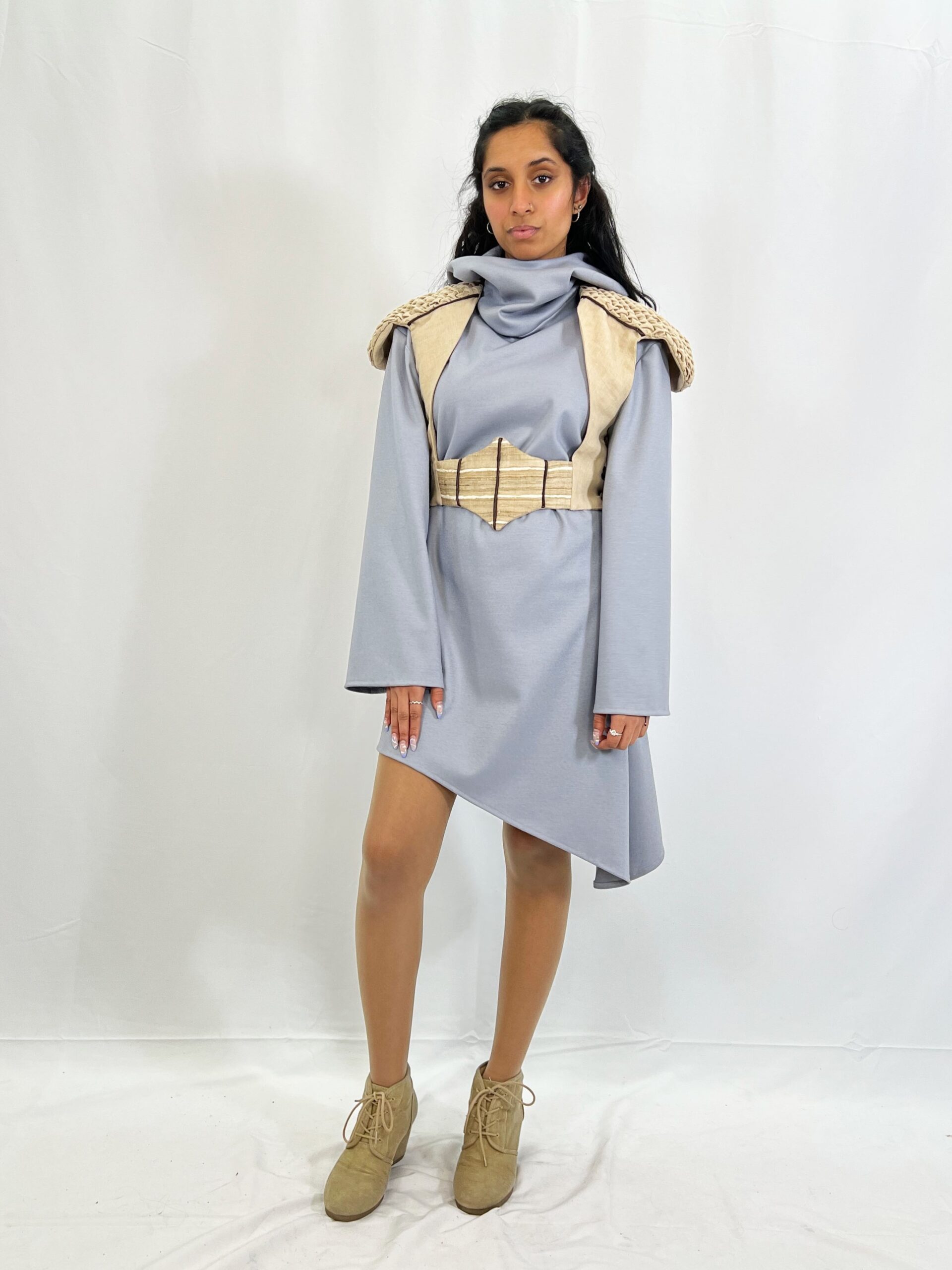 The Hortense look consists of a wool knit asymmetrical hooded dress, and of a linen vest with a contrasting raw silk belt, silk pipping, and hand-sewn smocking on the shoulders. Modelled by Alana Naraine.